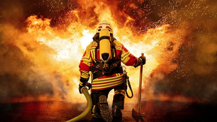 A firefighter kneels before the fire