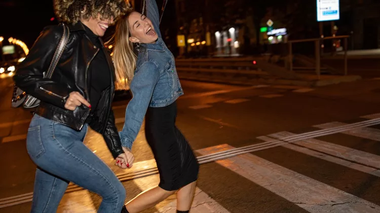 Drunk female friends crossing the street