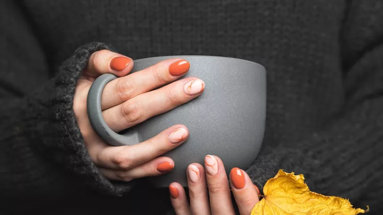 Woman holds a cup of hot tea. Grey knitted sweater
