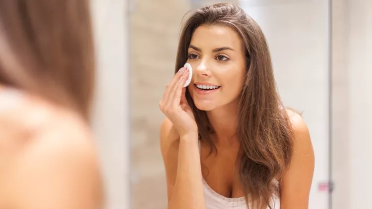 Beautiful brunette woman removing makeup from her face