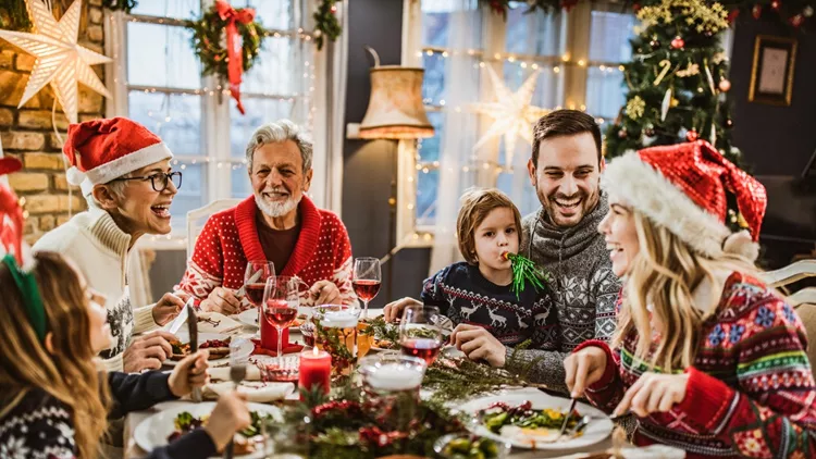 Happy extended family having New Year's lunch at dining table.