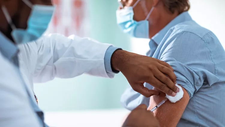 Mature man taking a vaccine from his doctor