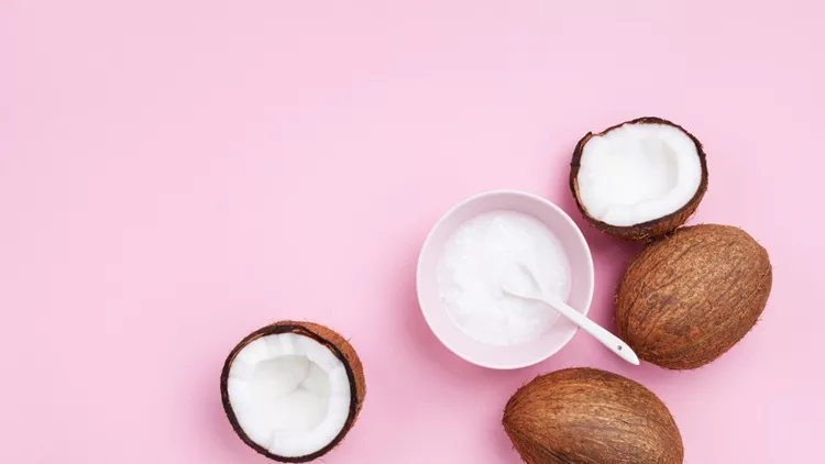 Coconuts fruit with coconut oil on pink pastel table top view. Beauty and spa organic cosmetic. Flat lay.