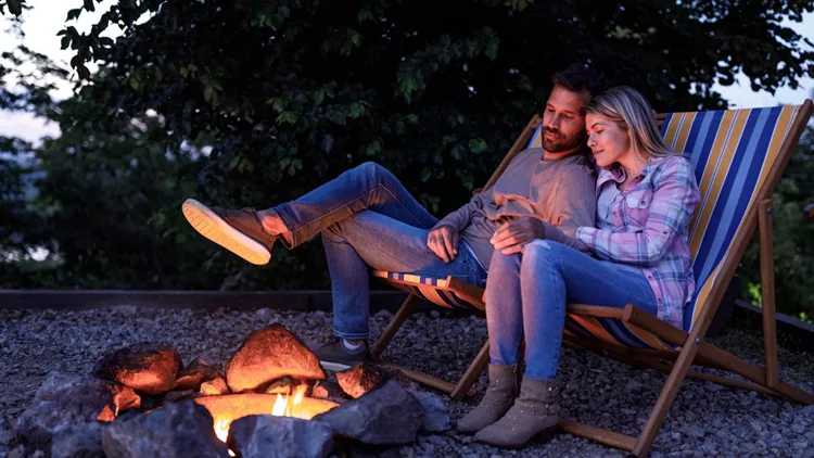 Young loving couple relaxing in deck chairs by the bonfire.