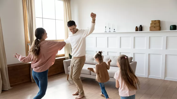 Funny active parents and children daughters dancing in living room