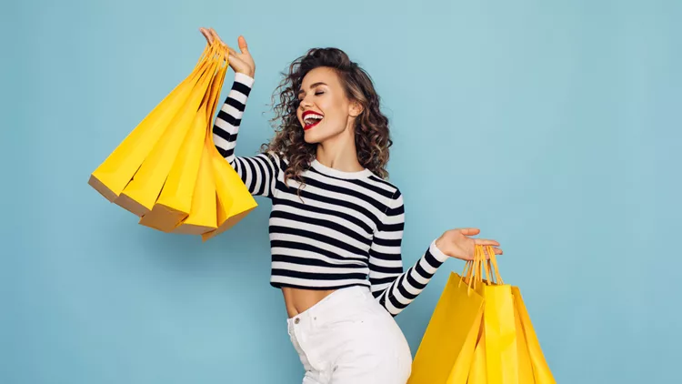 Conceptual photo of happy girl holds shopping packages on blue background