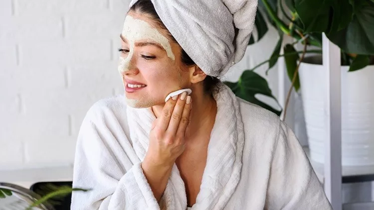 Young woman applying face mask at home